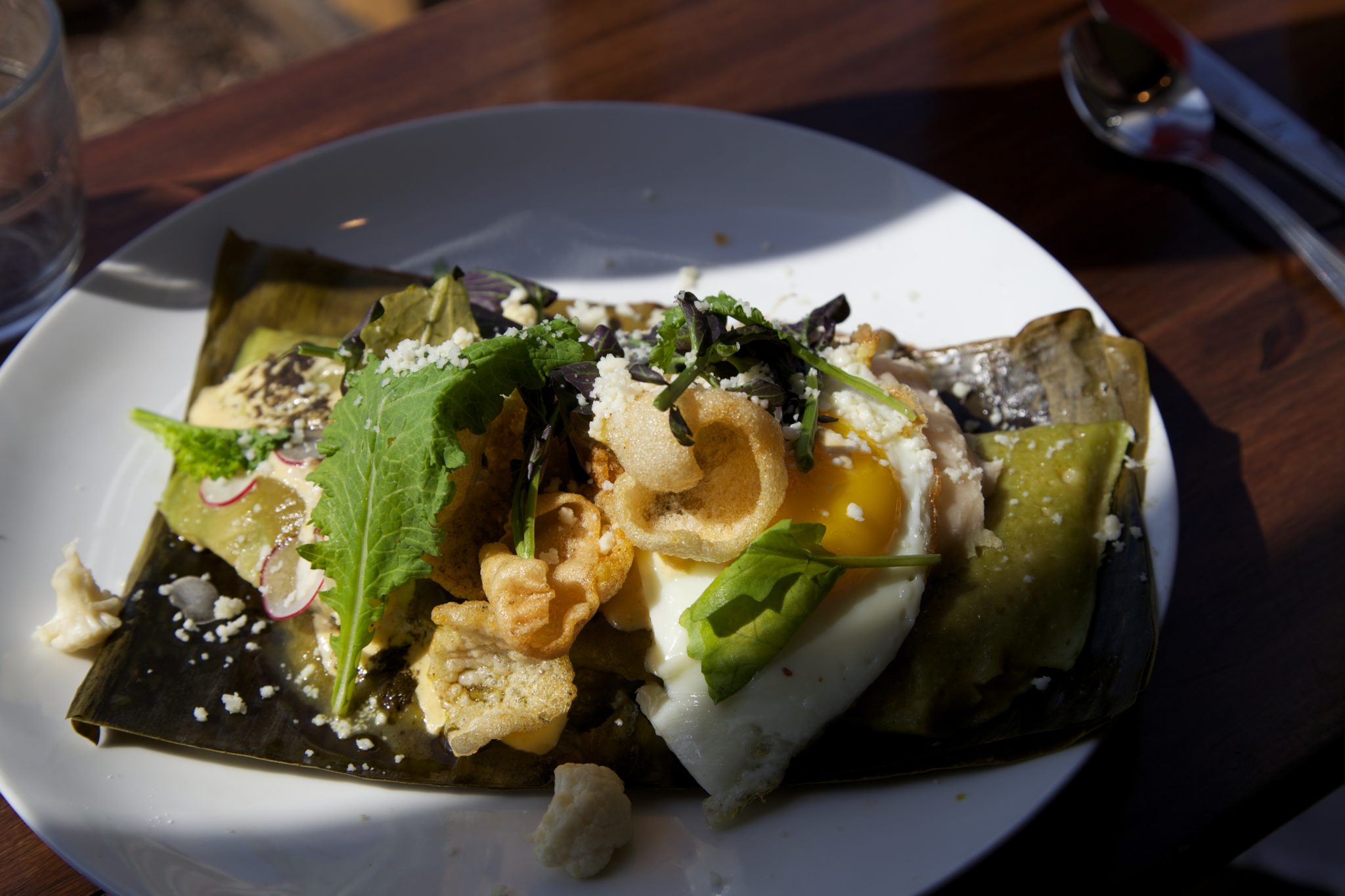 Spring Onion Tamale  Sunnyside egg, refried pinto beans, lime chicharonnes, Queso fresco, serrano chili aioli, pickled califlower